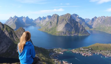 Female traveler sitting on top of a mountain staring onto the ocean overseas