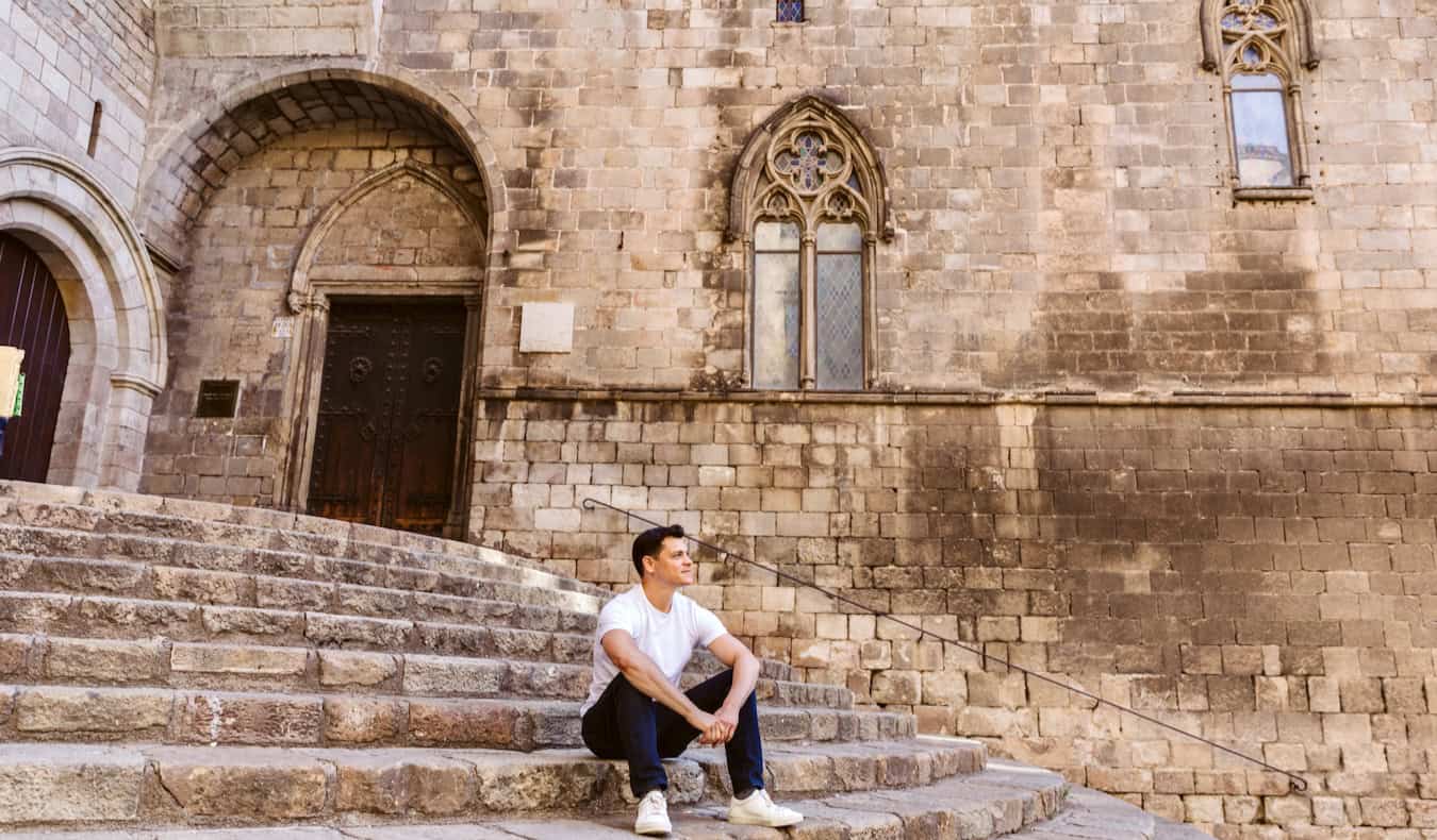 Nomadic Matt sitting on an old staircase outside in sunny Barcelona, Spain