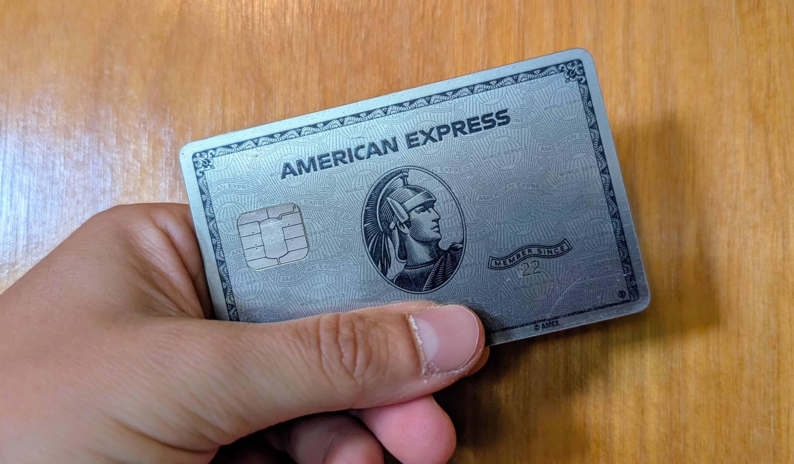 The Platinum Card by American Express being held up in front of a wood door