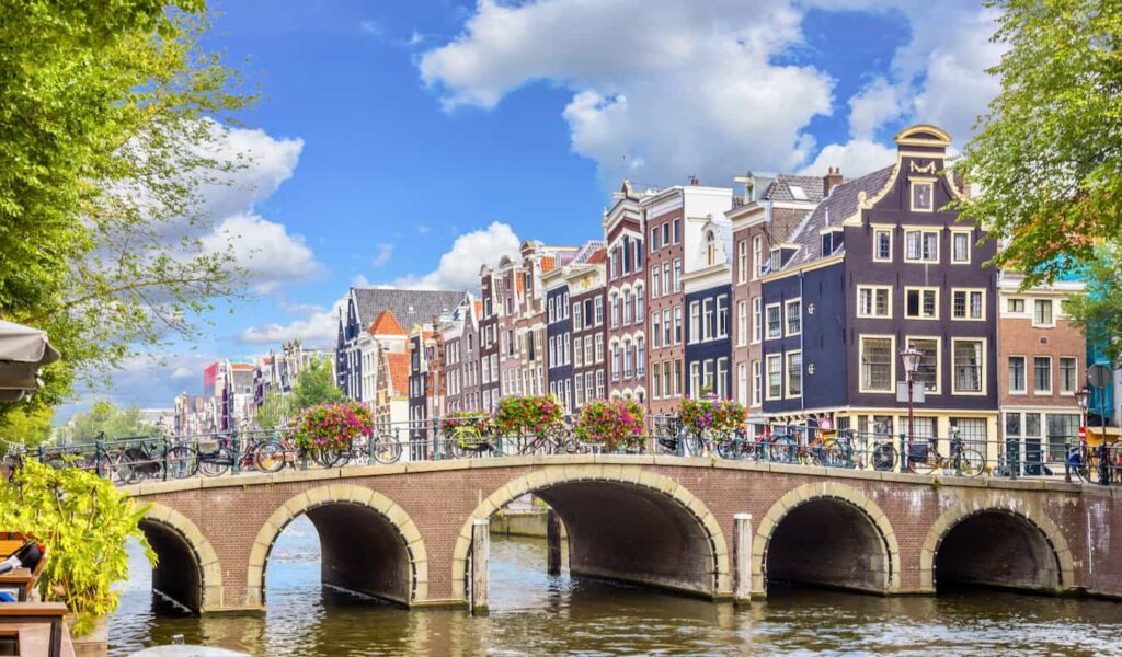 the canals of Amsterdam on a sunny summer day with row houses in the background