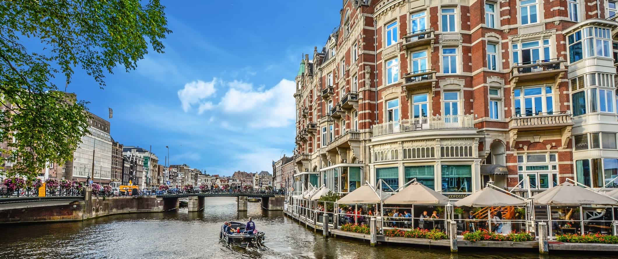 Boat cruising down a bend in a canal in Amsterdam, the Netherlands.