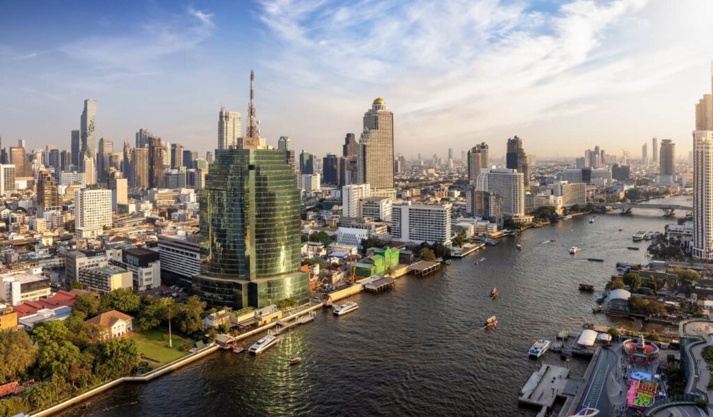 The skyline of Bangkok, Thailand, with skyscrapers rising on either side of a large, winding river