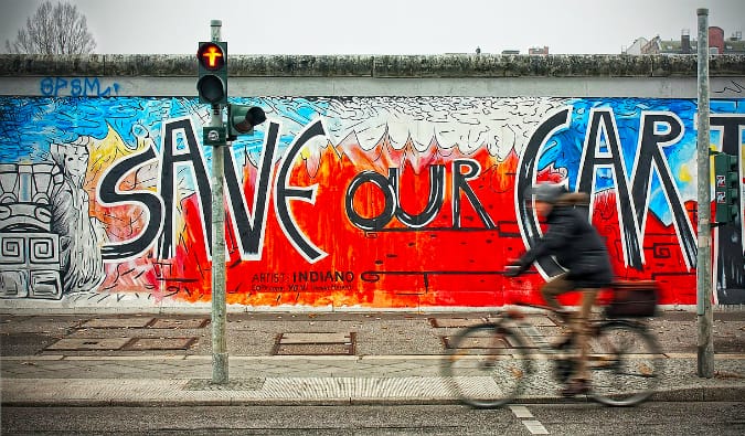 A person biking past a colorful mural at the East Side Gallery in Berlin, Germany