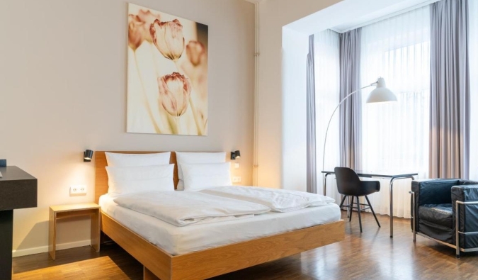 A minimally decorated guest room with hardwood floors and a large piece of floral artwork on the wall at Hotel Johann in Berlin, Germany