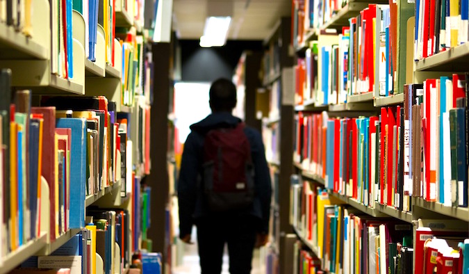 A man walking in a library full of books