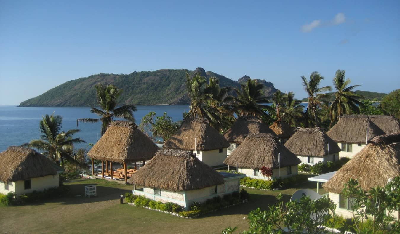 White huts with thatched roofs along the blue waterfront in Fiji