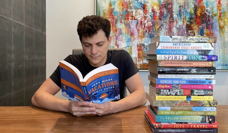 Nomadic Matt reading a pile of books inside at a big desk