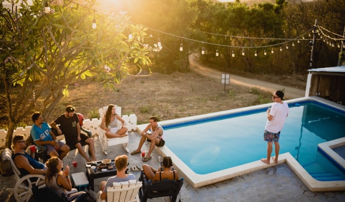 A group of budget backpackers relaxing at a pool in a hostel in Central America