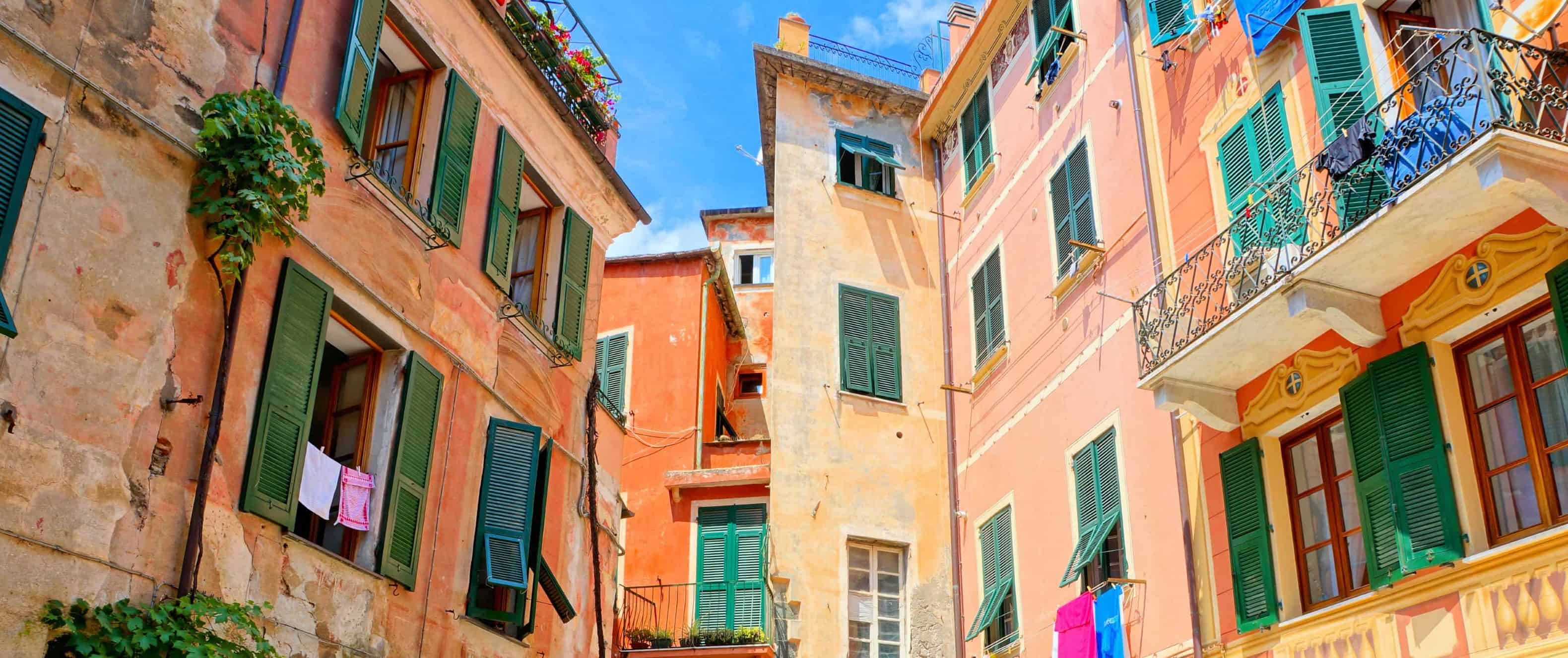 Colorful orange buildings and small square with a restaurant in Cinque Terre, Italy.