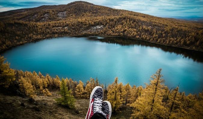 a travelers sitting on a hill overlooking a lake