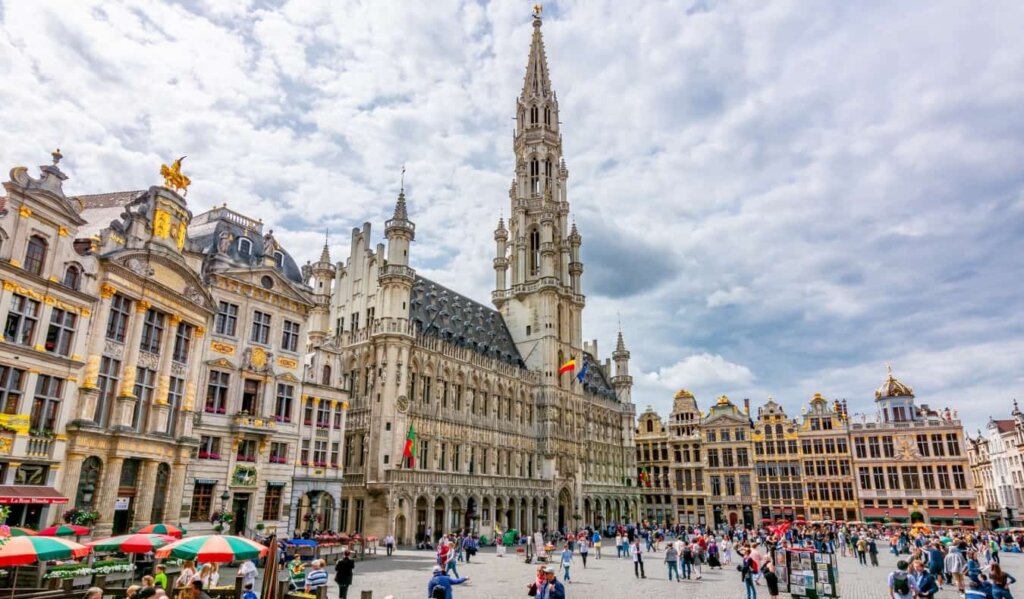 People walking around Grand Place, the central square in Brussels, Belgium lined with gilded and ornate buildings