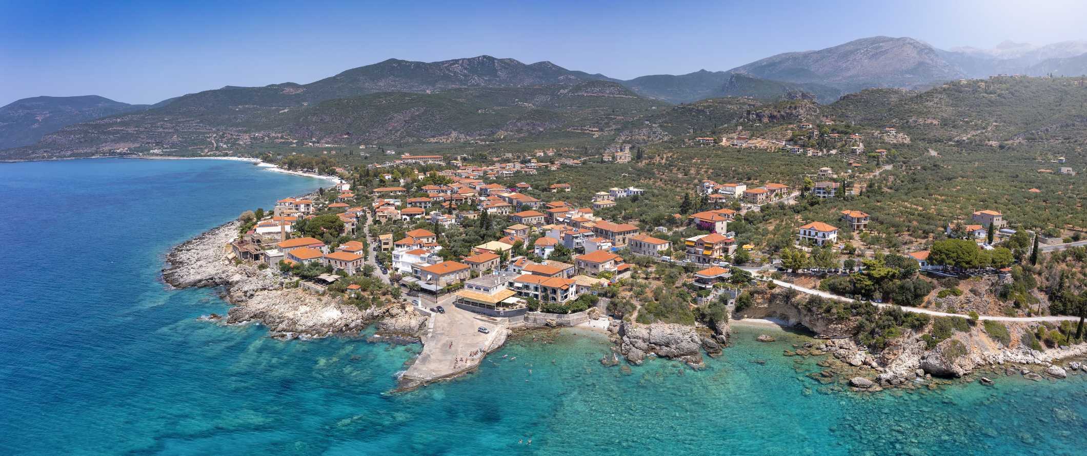 Aerial view of Greek town along the Mediterranean ocean, with mountains in the background