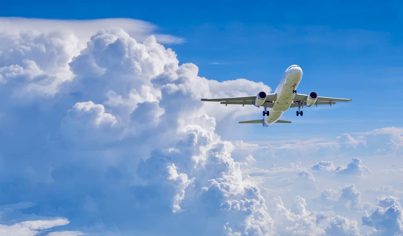 A commercial airplane flying in the bright blue sky