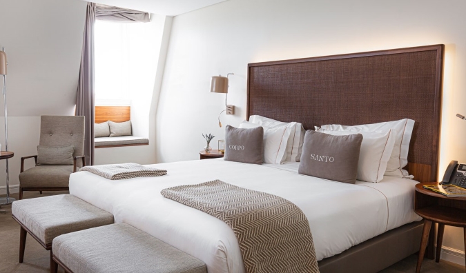 A minimally decorated guest room with a bed with pillows that say 'Corpo' and 'Santo' at Corpo Santo Hotel in Lisbon, Portugal