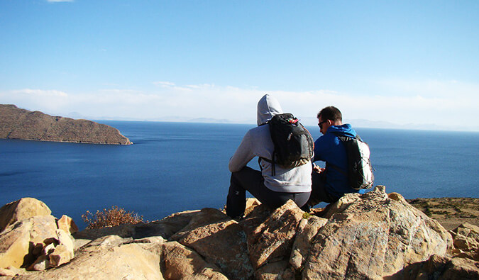 two man sat on a rock looking out over the sea