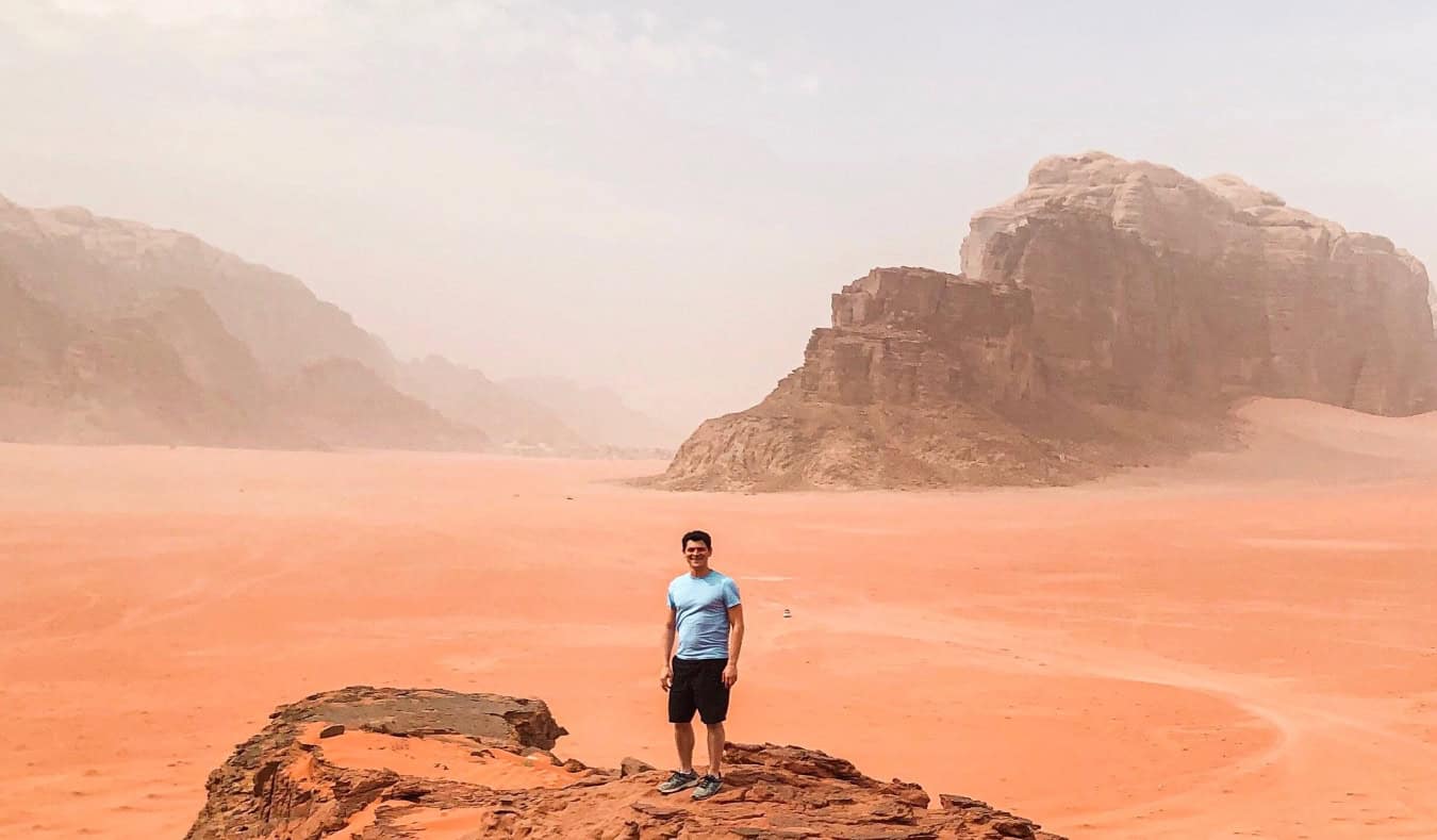 Nomadic Matt standing on a large rock formation in the desert in Jordan