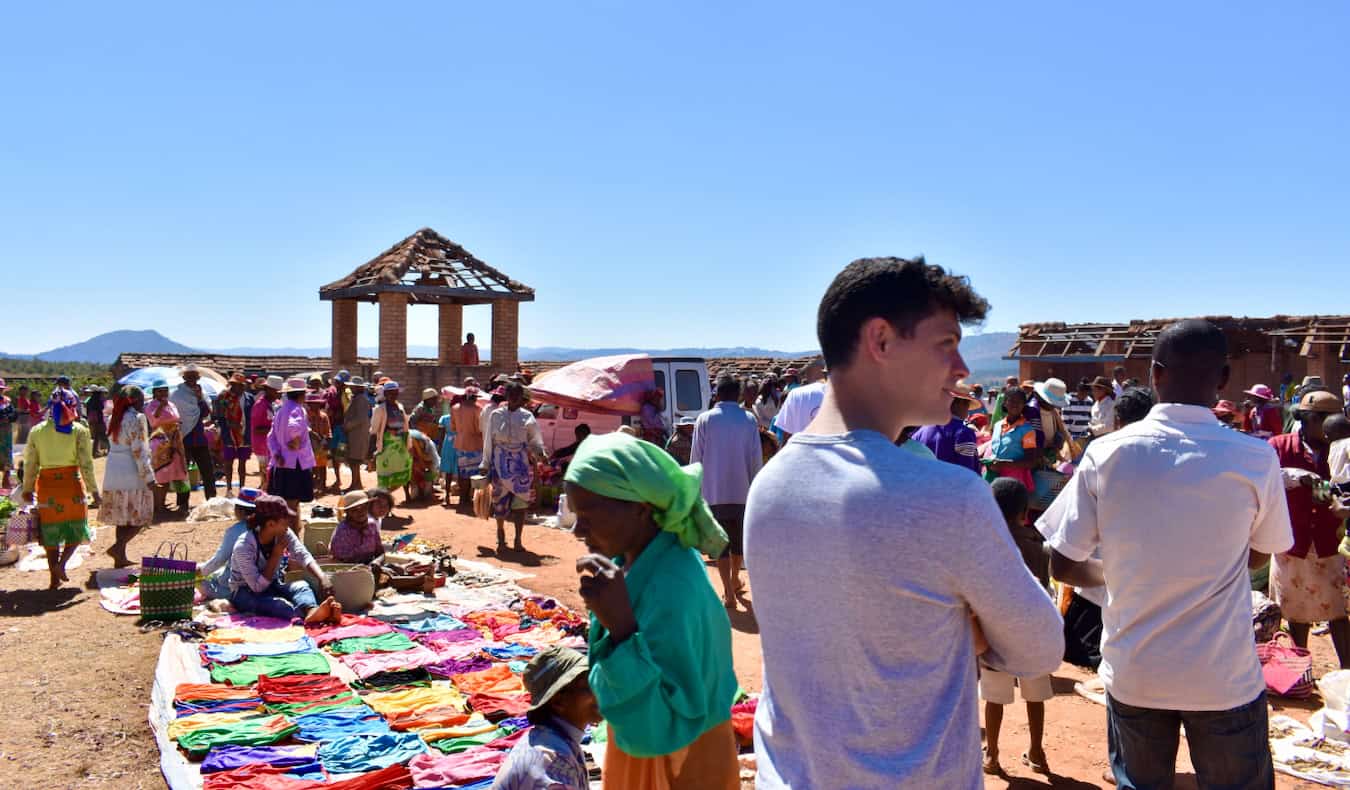 Nomadic Matt looking around busy and hectic market in sunny Madagascar