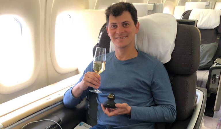 Nomadic Matt sitting in business class holding a glass of champagne and a rubber duck