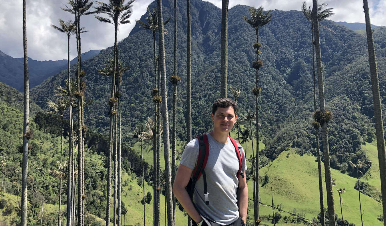 Nomadic Matt standing in front of a grove of tall trees in the lush mountains of Colombia