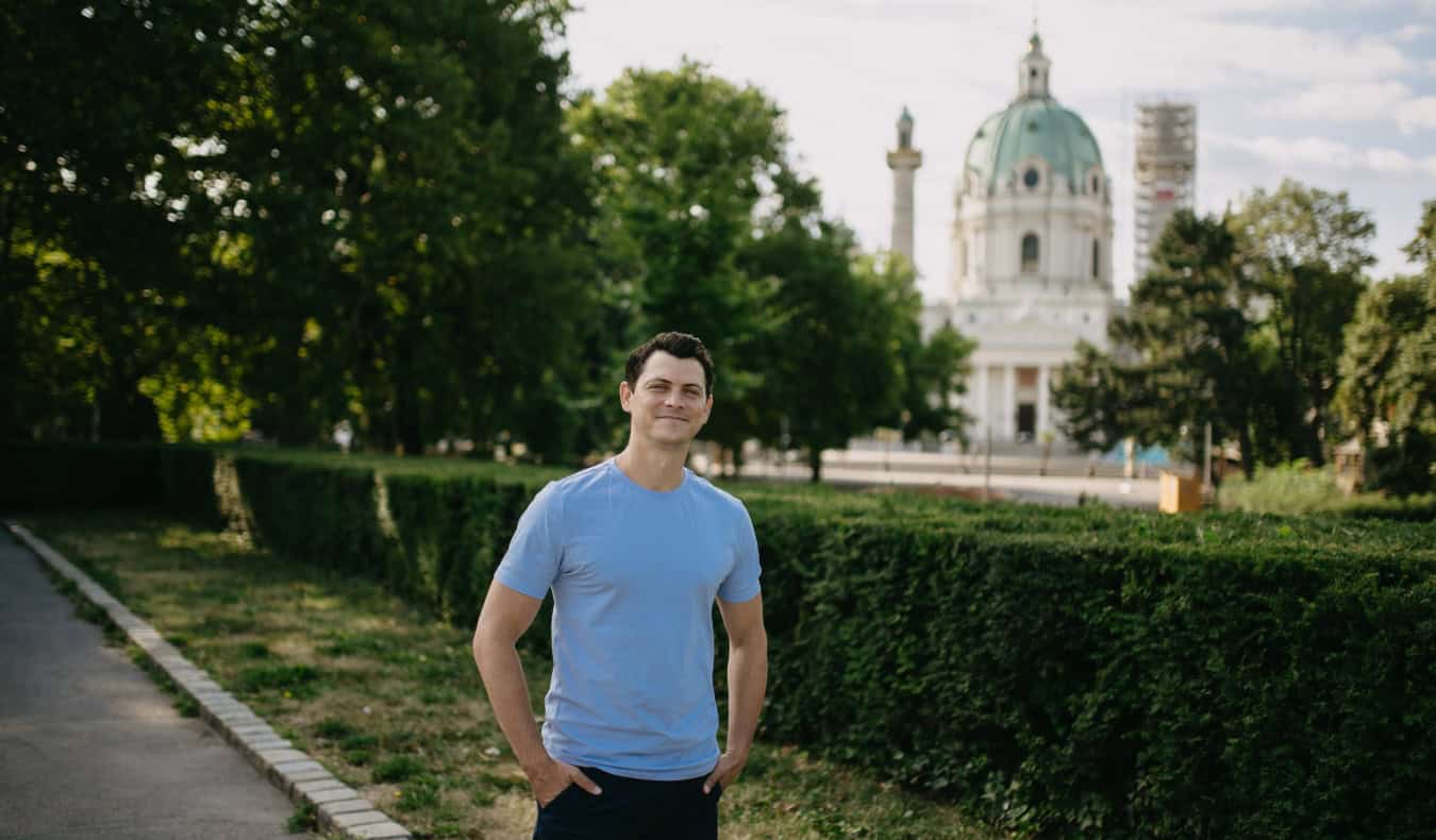 Nomadic Matt standing in a park in Vienna with a church in the background