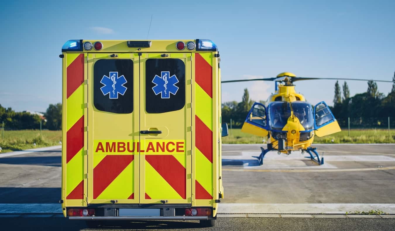 An ambulance parked next to a helicopter on a medical evacuation width=