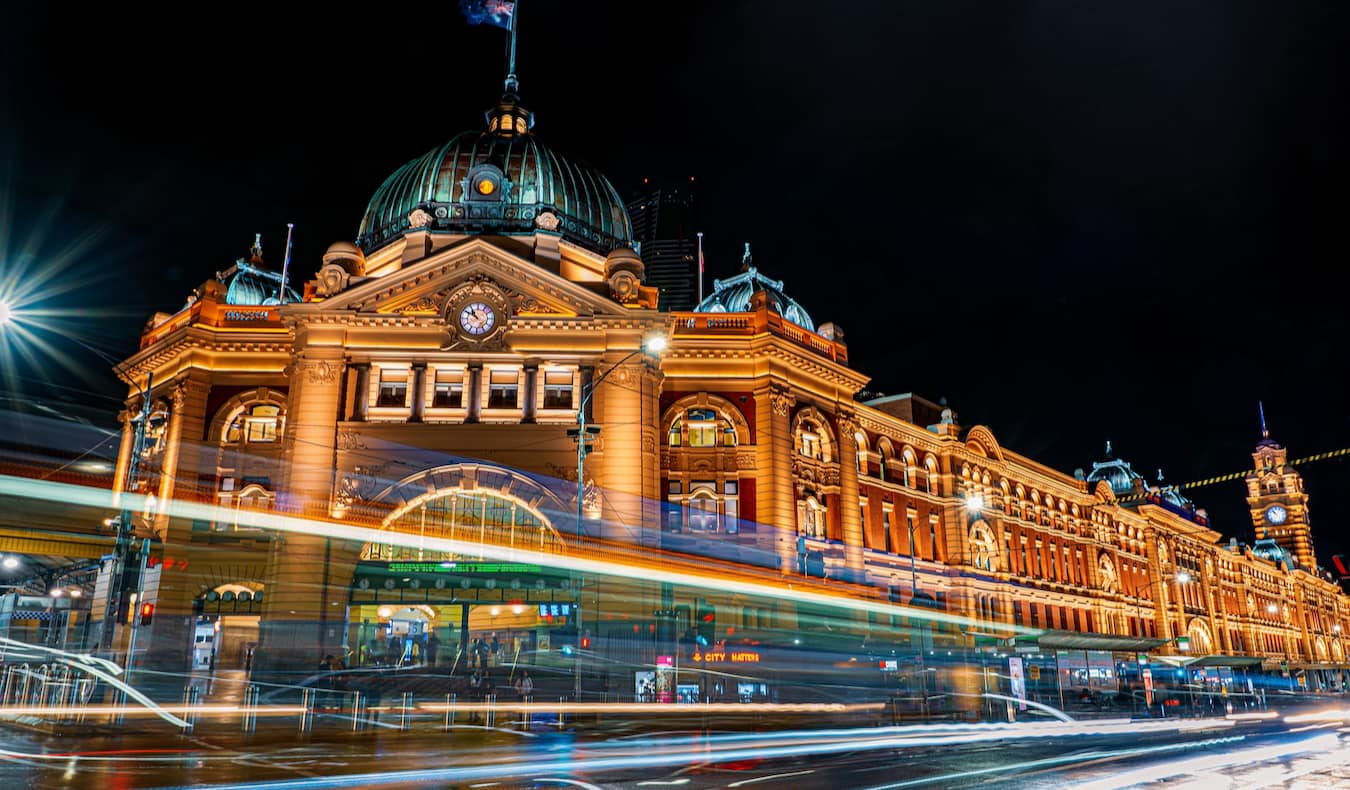 The historic Flinders Street Station in Melbourne, Australia at night with traffic passing by