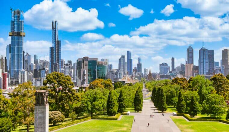 People exploring a wide-open park near the war memorial in sunny Melbourne, Australia