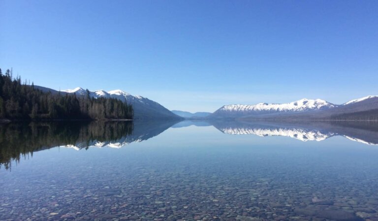 A crystal clear lake lined with snow-capped mountains in Montana, USA