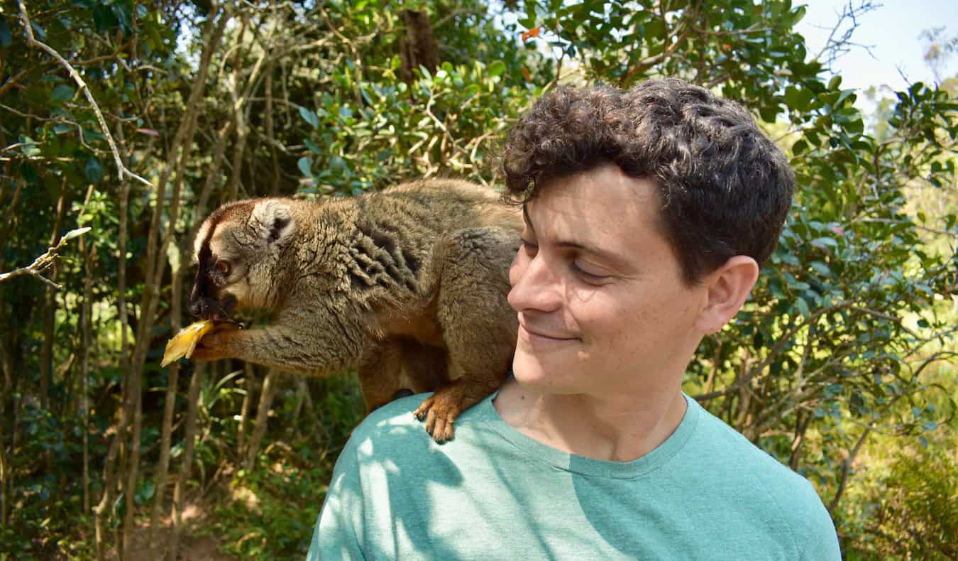 Nomadic Matt posing with a small lemur in lush Madagascar, Africa