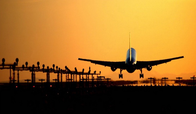 A commercial plane taking off into the golden, bright sunset