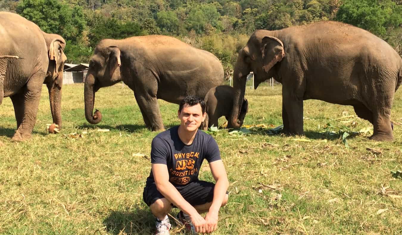 Nomadic Matt posing near some elephants at a sanctuary in rural Thailand after he quit his job to travel