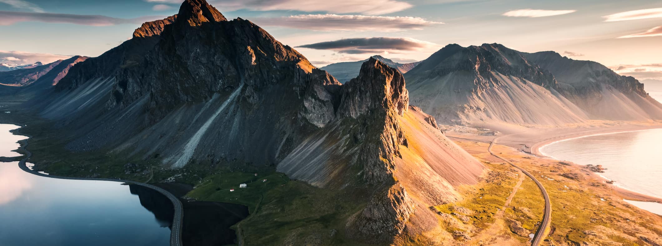 A wide, open road curving around a towering mountain in moody Iceland