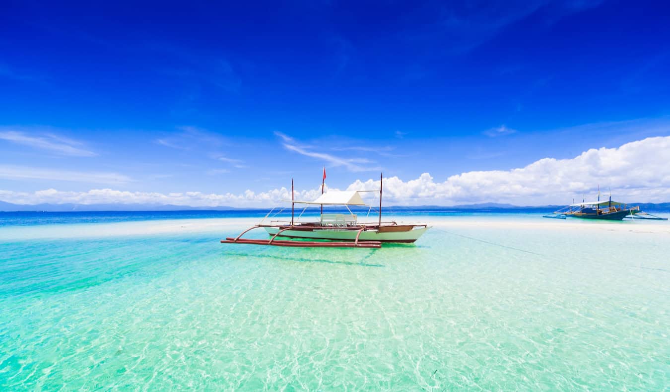 A small boat beached in the stunning, clear waters along the coast of Boracay on a bright and sunny day