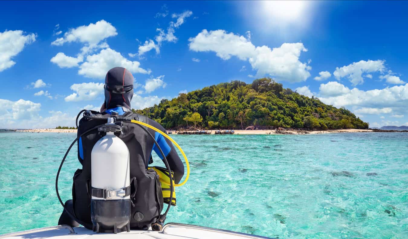 A scuba diver sitting on the edge of their boat as they get ready to go diving in the ocean