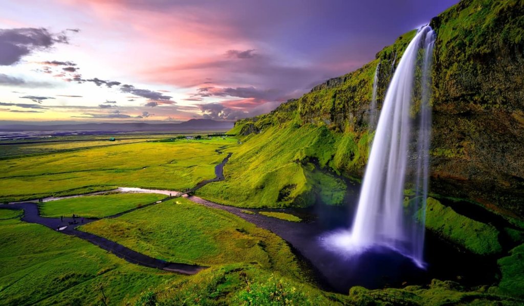 Icelandic waterfall with green landscape and sunset