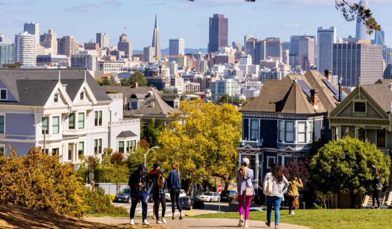 People out walking around sunny San Francisco with the towering downtown in the distance