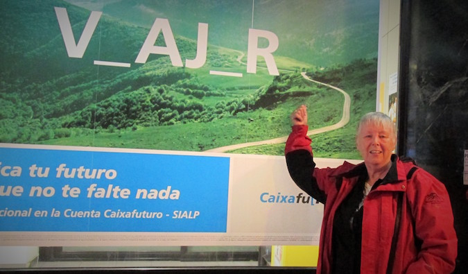 A senior solo female backpacker posing near a sign overseas