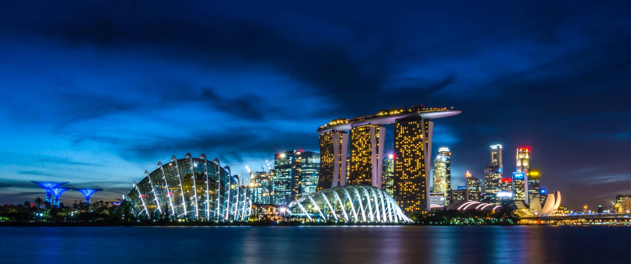 The skyline of urban Singapore, featuring skyscrapers all lit up at night