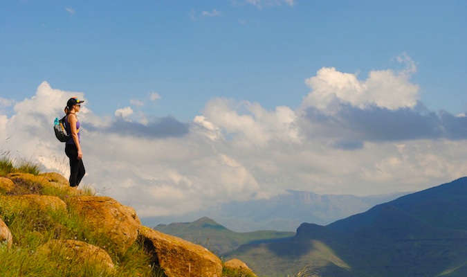 Woman looking onto the sunset and clouds at the top of Tabel Mountain while traveling