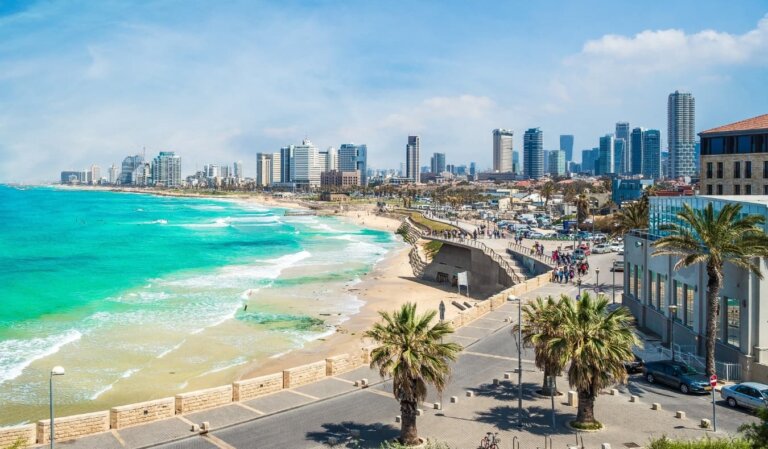 The city skyline in Tel Aviv, Israel, with a horseshoe-shaped beach, the azure blue ocean, and skyscrapers in the background