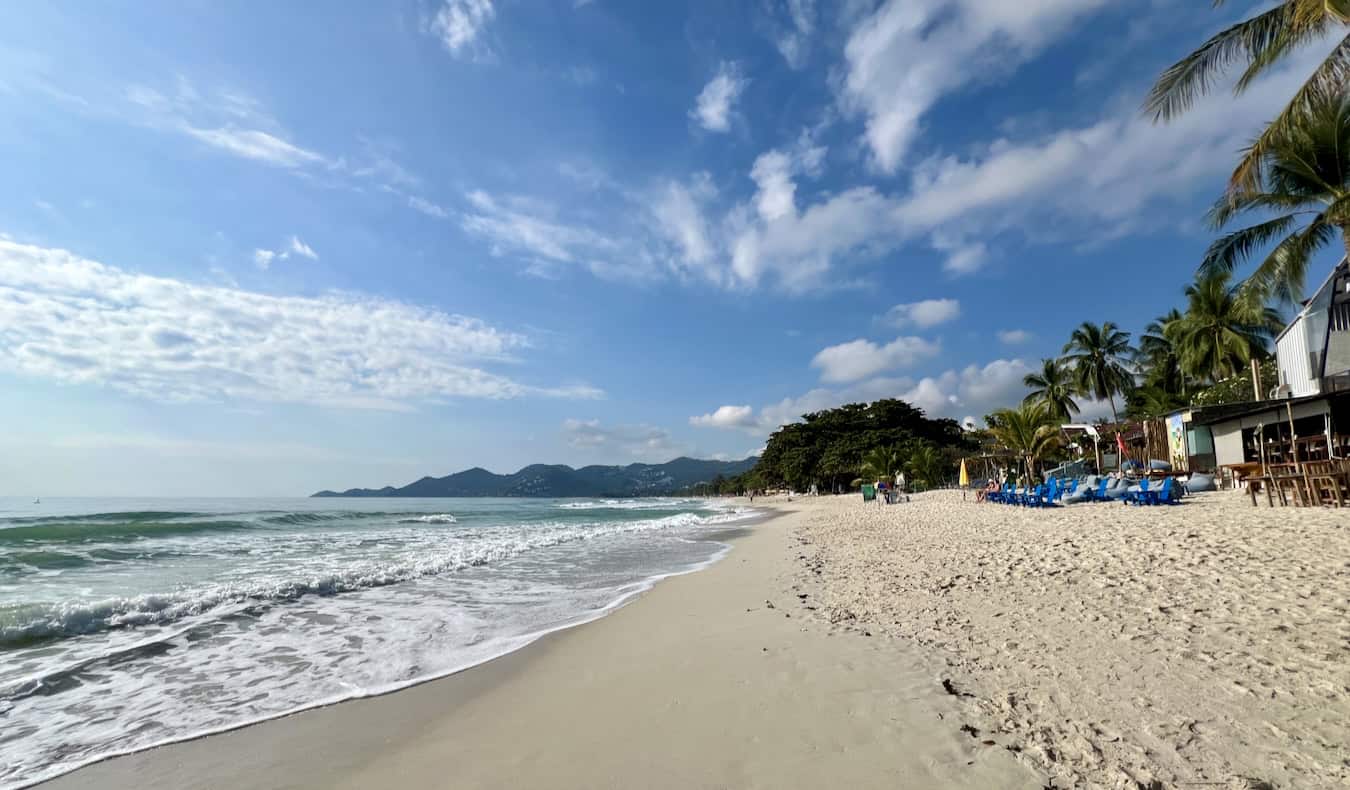 A wide and empty white sand beach in sunny southern Thailand on an island