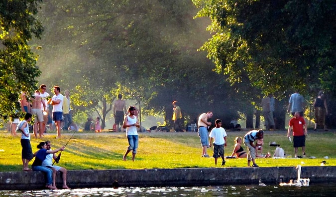 People hanging out, talking, and fishing along the banks of the Spree River in TrepTower Park in Berlin, Germany