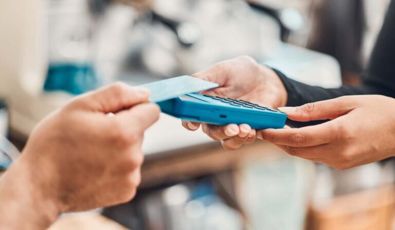 someone tapping a credit card to pay on a credit card reader