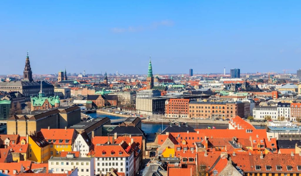 Aerial view of Copenhagen, Denmark, with red rooftops and church steeples dotting the cityscape